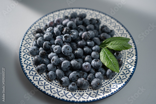 Freshly picked blueberries arranged artfully on a decorative plate with green leaves, showcasing vibrant colors and textures in a cozy kitchen setting