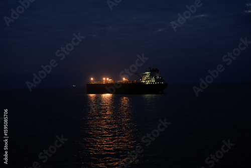 illuminated cargo ship sailing in the ocean at night under a starlit sky