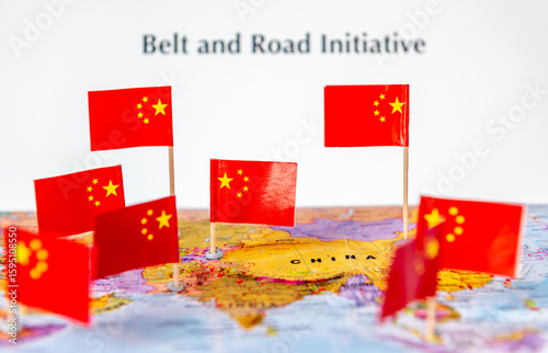 Photography A Belt And Road Initiative concept with the Chinese national flags on various parts of a world map and the words belt and road initiative in the background