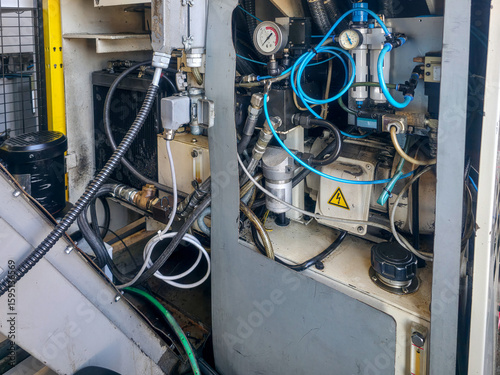 Industrial machinery with intricate hydraulic systems and hoses in a manufacturing facility during daytime