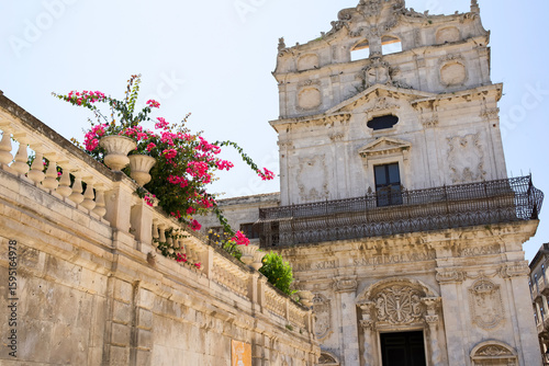 Photos Historic building with ornate architecture and vibrant flowers in pots against