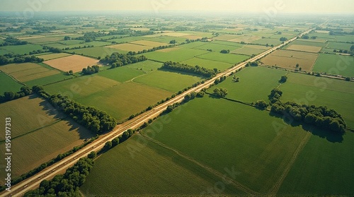 Aerial view of a road cutting through a patchwork of green and brown fields.