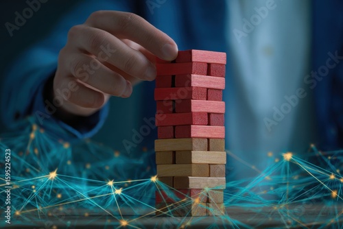 Hand carefully places a red wooden block on a tall unstable tower of blocks with glowing digital network in background
