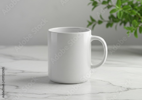 A clean white ceramic mug rests on a marble surface with a plant in the background