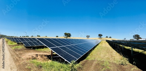 Centrale solaire avec éolienne en arrière-plan, symbole d’énergie renouvelable