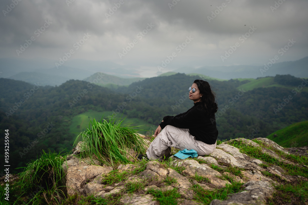 Fototapeta premium Indian woman resting at a windy forest trek viewpoint in Vagamon, Idukki, Kerala