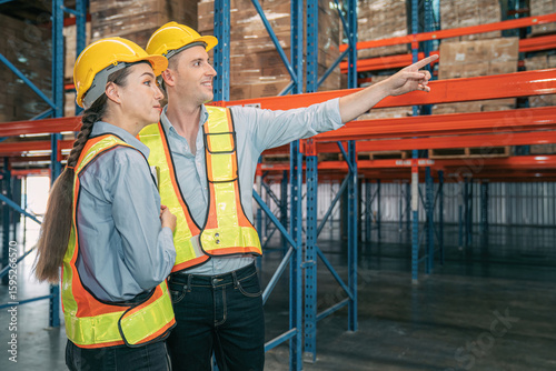Confidence caucasian man, woman staff worker wear safety helmets, vest show teamwork collaborate, cooperation in logistics inventory operation. show success, efficiency in modern warehouse management.