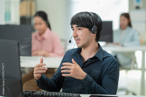 Fotografía Happy businessman with headphones working on PC in call center office, young mal