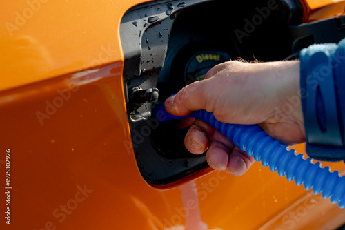 Driver filling adblue tank of the modern orange diesel car