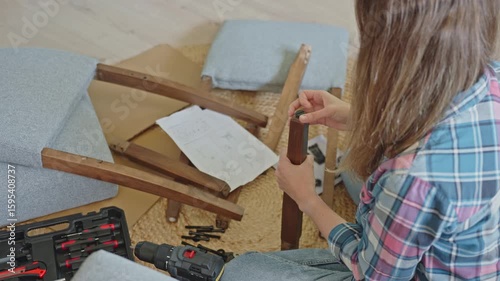 Woman assembling chair by hand using manual tools at home
