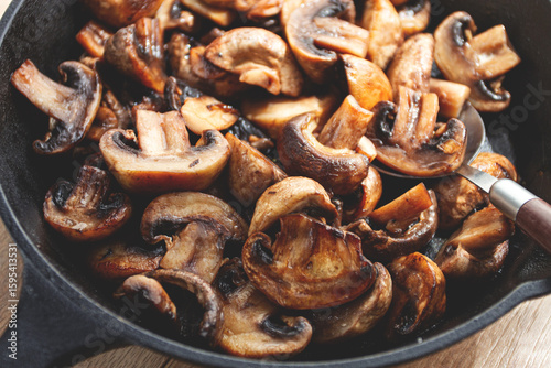 fried mushrooms champignons. on a cast-iron frying pan, natural light, close-up,