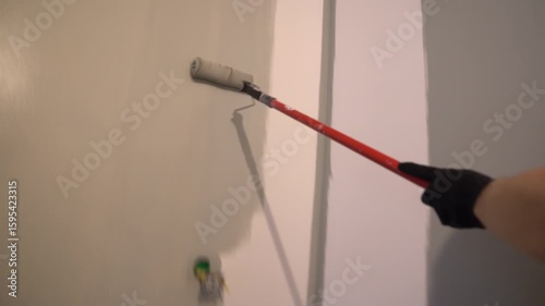 Painting walls with a paint roller for perfect wall painting. Roller movement from top to bottom. Grey paint on the surface. High quality 4k footage