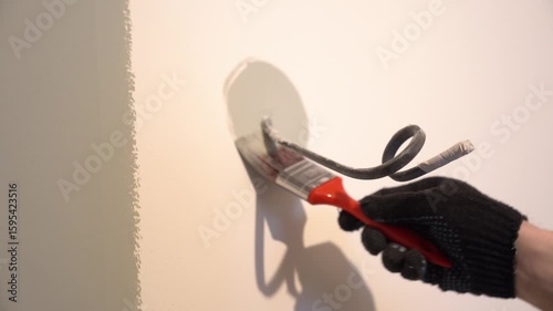 Painting the walls with a brush around the wire. Apartment renovation. A black electric power wire is sticking out of the wall. High quality 4k footage
