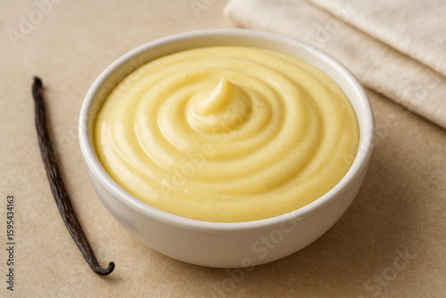 Bowl of vanilla pastry cream with vanilla pod displayed on table