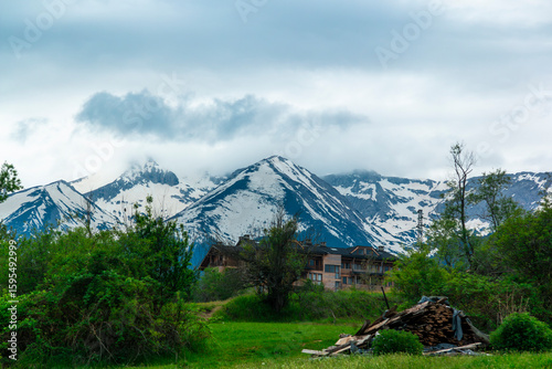 View of guesthouses and trees in a valley below the Pirin Mountains, seen from a hiking trail near the touristy town of Bansko in southeastern Bulgaria