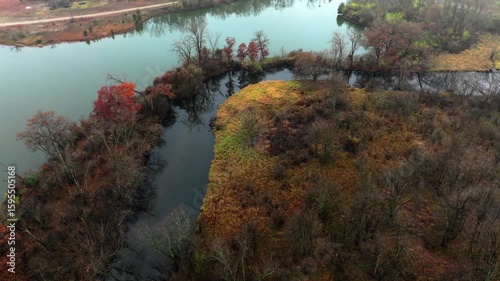 Aerial footage of forested land near Jackson Michigan on a foggy day in late autumn. The grand river snaking through colorful trees