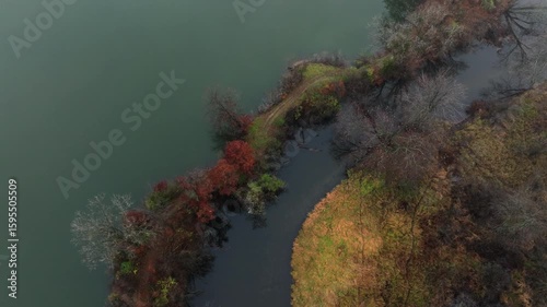 Aerial footage of forested land near Jackson Michigan on a foggy day in late autumn. The grand river snaking through colorful trees