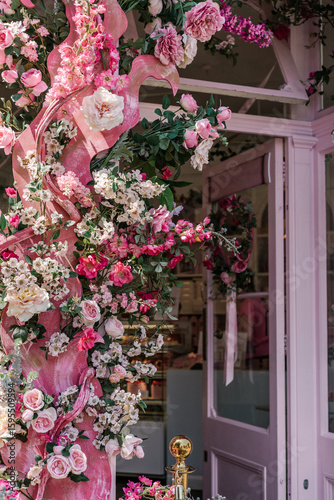 A café entrance with a pink door and pink aesthetic, adorned with pink flowers.