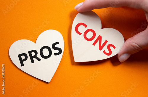 Pros vs Cons symbol. Concept word Pros vs Cons on wooden hearts. Businessman hand. Beautiful orange background. Business and Pros vs Cons concept. Copy space