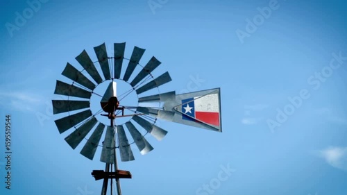 A texas flag adorns a vintage windmill against a clear blue sky