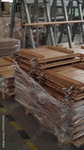 Vertical video showing a stack of freshly manufactured wooden cabinet doors wrapped in protective plastic film, placed on a warehouse floor in a furniture production facility.
