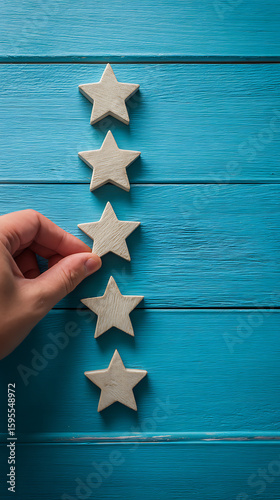 Hand placing wooden star on blue painted wooden surface represents excellent quality or achievement concept