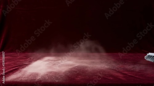 Close up of a carpet beater hitting a red velvet surface with dust particles floating around it