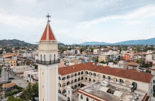 Fototapeta Naklejka Na Ścianę i Meble -  Aerial view showcases the Saint Dionysios church tower's red roof against the backdrop of Zakynthos town, surrounded by a sprawling urban landscape in Greece