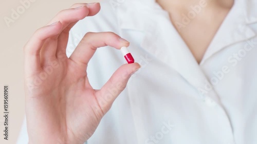 A woman's manicured hands hold a bottle of pills, highlighting health and beauty care
