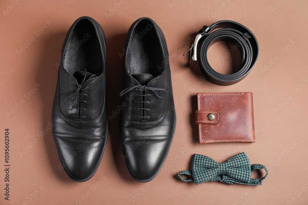 Pair of black leather shoes, belt, bow tie and purse on dark beige background, flat lay Pair of black leather shoes, belt, bow tie and purse on dark beige background, flat lay