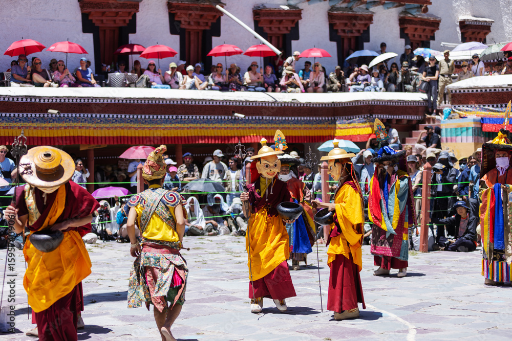 Fototapeta premium Monks in colorful costumes and masks perform a traditional dance during the Hemis Festival in Leh, Ladakh. The vibrant cultural celebration draws crowds who gather to witness this sacred ritual.