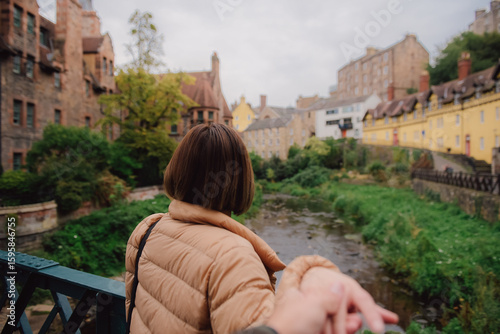 Woman leading man to the dean village in edinburgh. Woman in down jacket clothes leading man to the dean village in edinburgh, Scotland. Traveling together. Follow me.