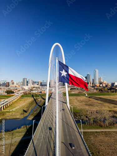 Texas state flag and Modern Margaret Hunt Hill Bridge over Trinity river in Dallas, Texas on a sunny day.