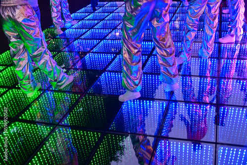 Foto Unrecognizable group of people dancing on colorful LED lights dance floor