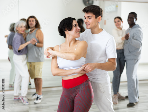 Photos Happy caucasian guy and girl practising paired latin dance in dance studio