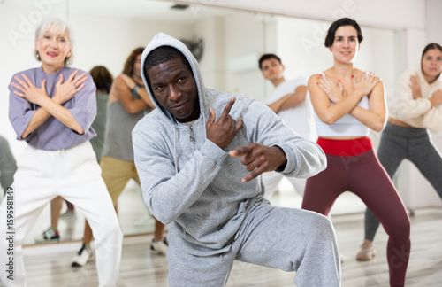 Tableau sur toile African-american guy doing hip-hop dance moves with other people in dance studio