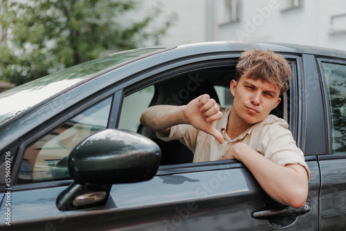 Sad young driver showing thumbs down in car. Bad customer service by repair shop