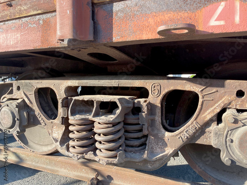 фотографія A close-up of a rusted train bogie with visible springs and wheel assemblies, il