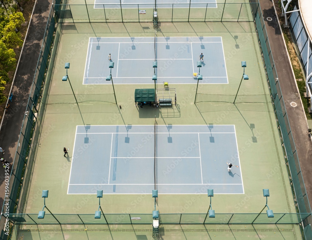 Naklejka premium Aerial view of tennis courts with players in action.