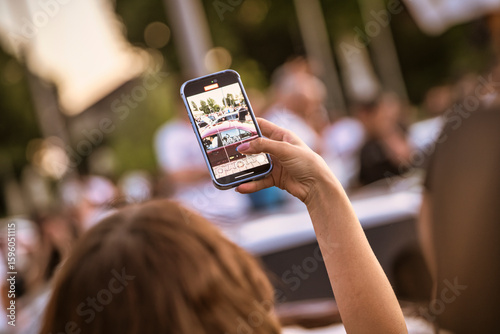 Woman recording live event with smartphone in blurred background