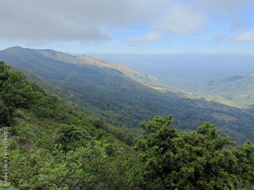 Naklejka premium Stunning panoramic view of lush mountains under a partly cloudy sky in a remote wilderness during the day