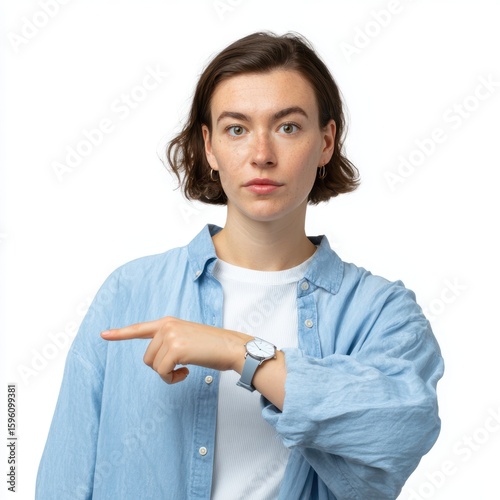 A woman in casual attire pointing to her watch, conveying urgency, isolated on a white background. Time, deadline.