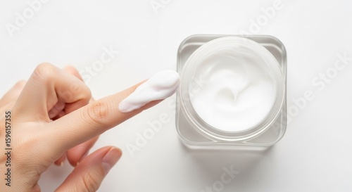Woman Applying White Skincare Cream from Jar with Clean Minimal Background
