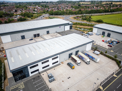 Aerial View of Modern Industrial Estate with Warehouses, Loading Bays, and Delivery Trucks near Residential Area