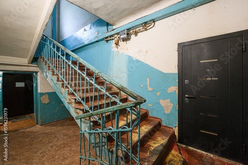 Canvas Print Worn staircase in an old building with peeling blue paint and a dark door