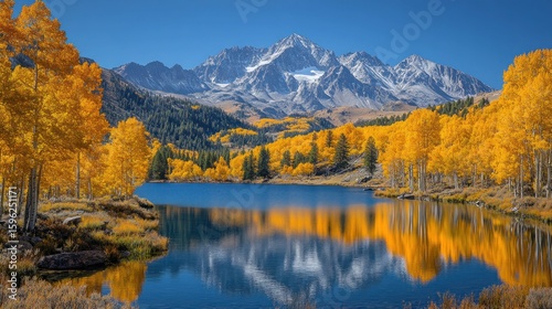 Golden aspen trees frame a mountain lake reflecting a snow-capped peak