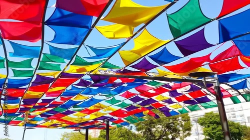 Colorful canopy of vibrant flags against a bright blue sky.