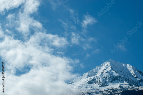 Snowy mountain peak with blue sky and clouds.