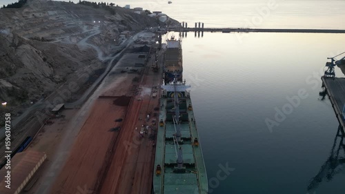 Unloading of the vessel in the port with the help of shore cranes. Open holds with cargo.