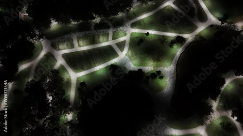 Bursa's Nocturnal Park Maze: A Drone's Zenithal Glimpse Over Luminous Paths Surrounding a Darkened Pond Amidst Silhouetted Trees Evoking Urban Serenity and Intricate Green Spaces